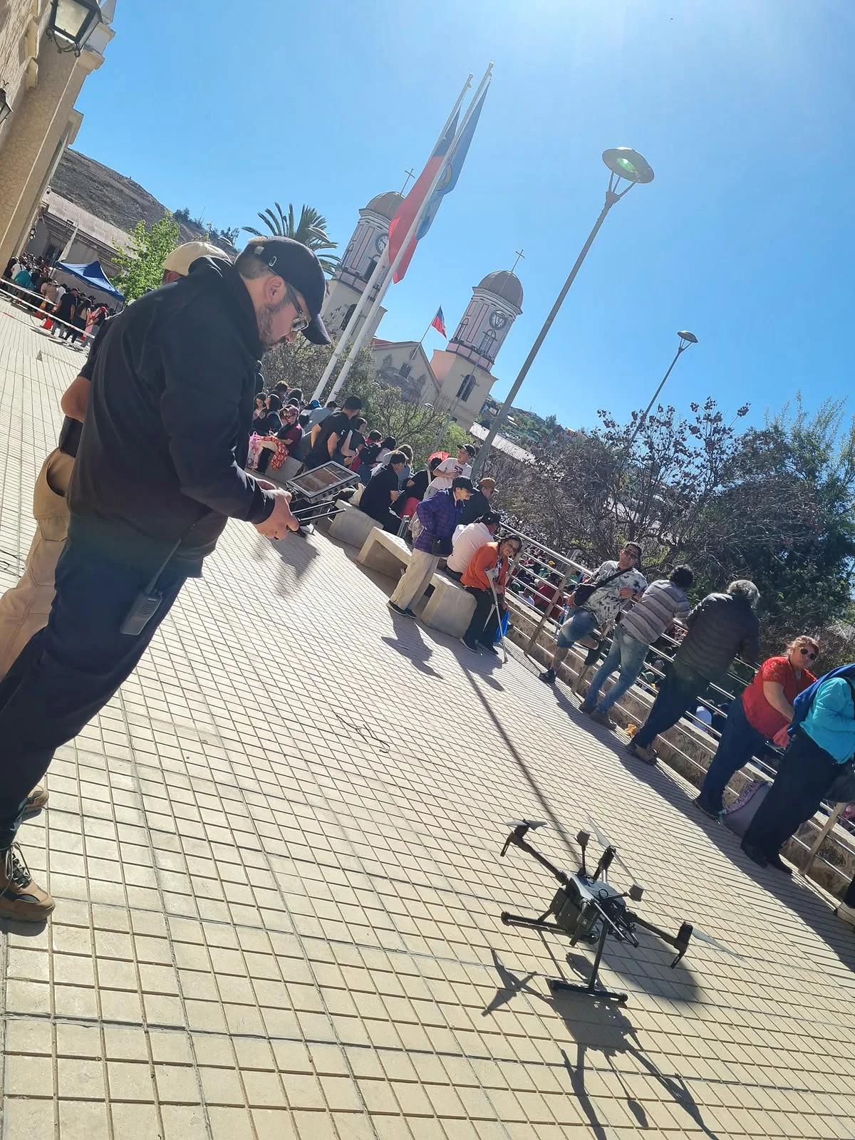 Operador con control junto a un dron situado en una plaza pública