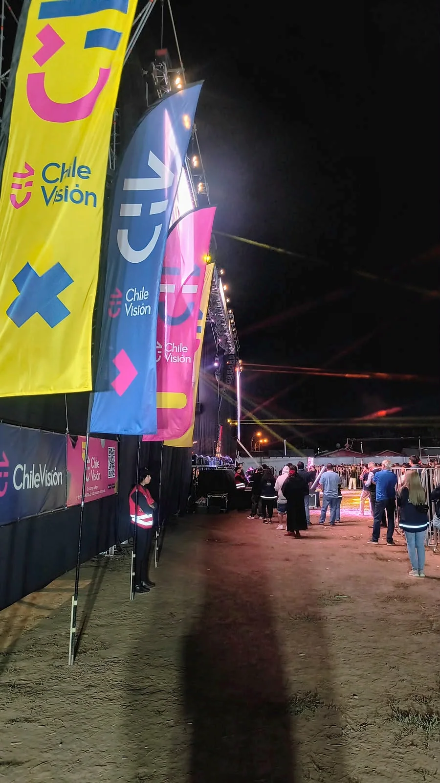 Personal de seguridad en zona lateral de escenario con banderas y luces