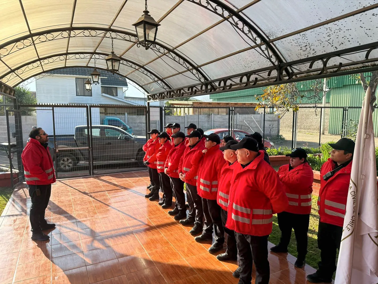 Personal en uniformes rojos reunido bajo una cubierta mientras escucha a un coordinador