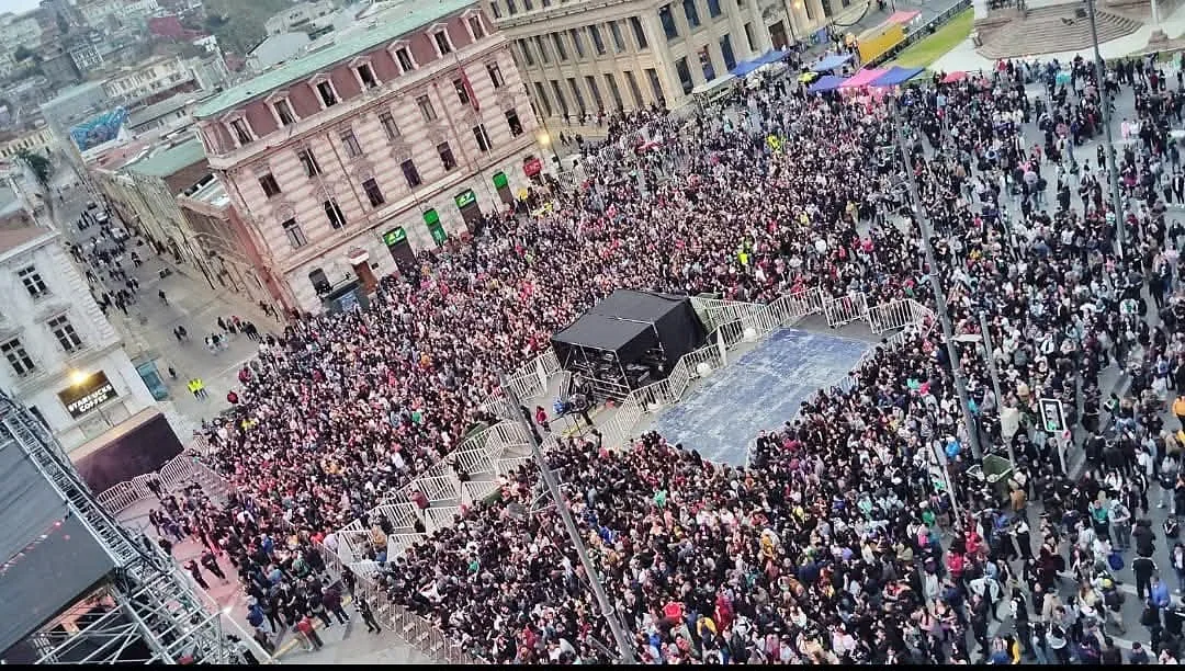 Vista elevada de un público numeroso y vallas de contención en plaza urbana