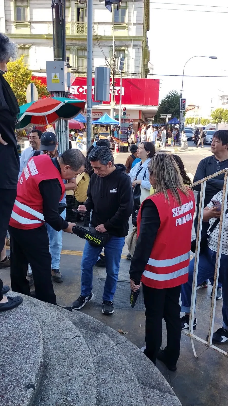 Guardias con chalecos rojos realizando control con detector manual en calle