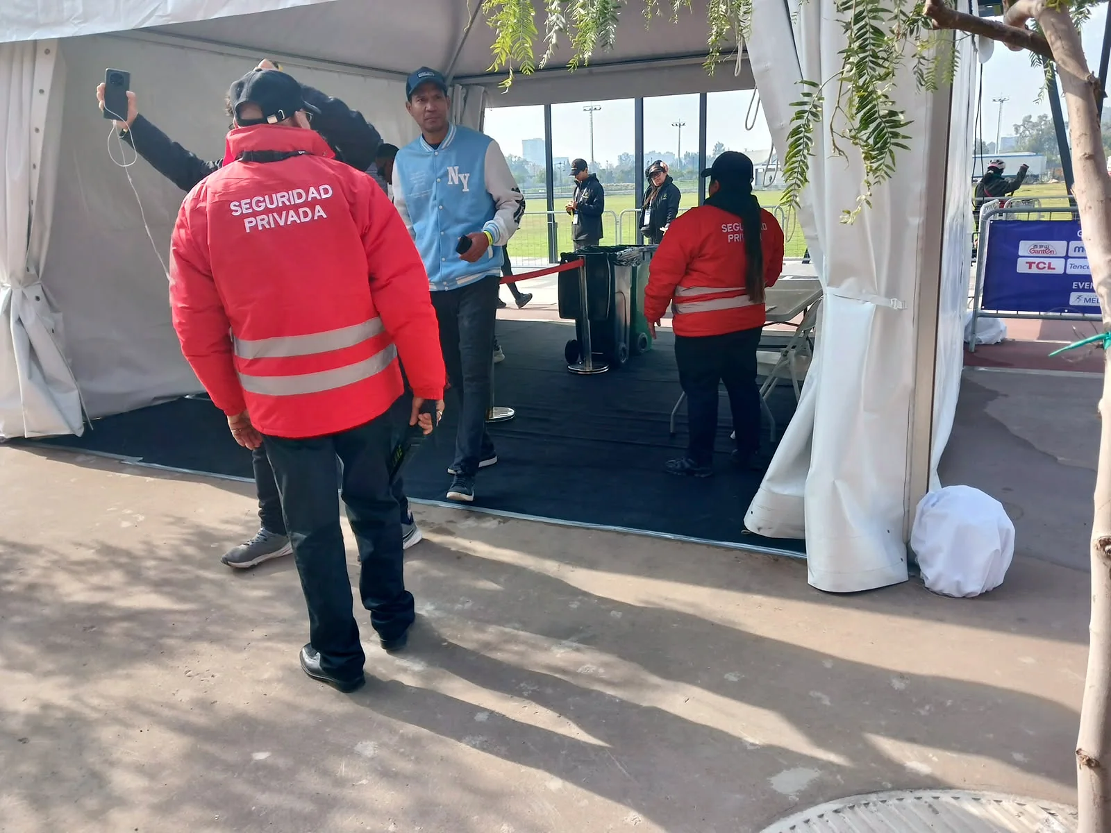 Personal con chaquetas rojas coordinando la entrada bajo una carpa blanca