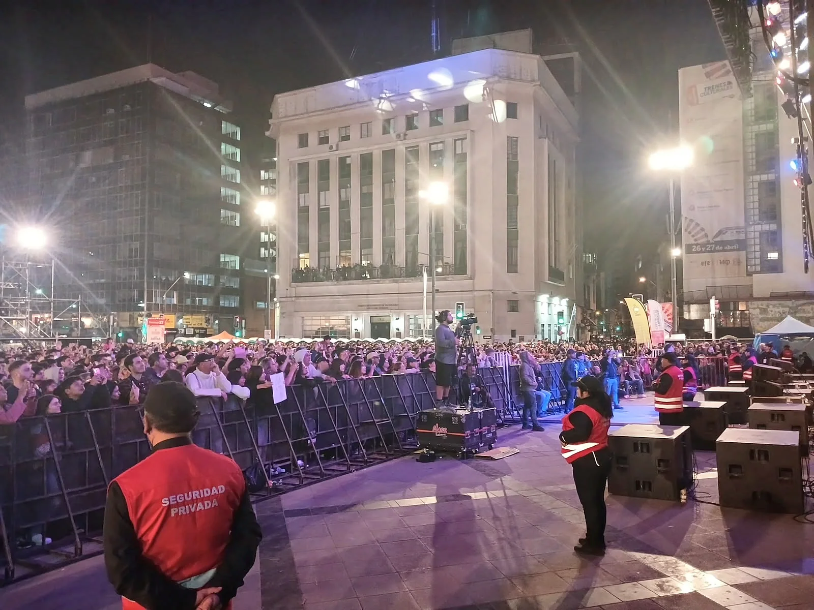Guardias ubicados cerca de vallas y público en concierto nocturno